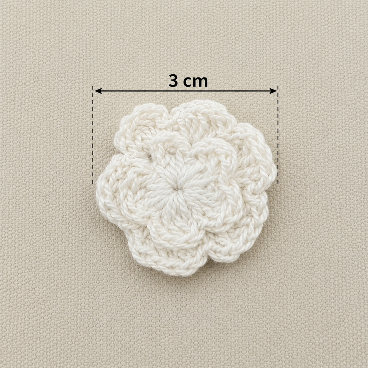 White crocheted flower with a measurement label on a beige background