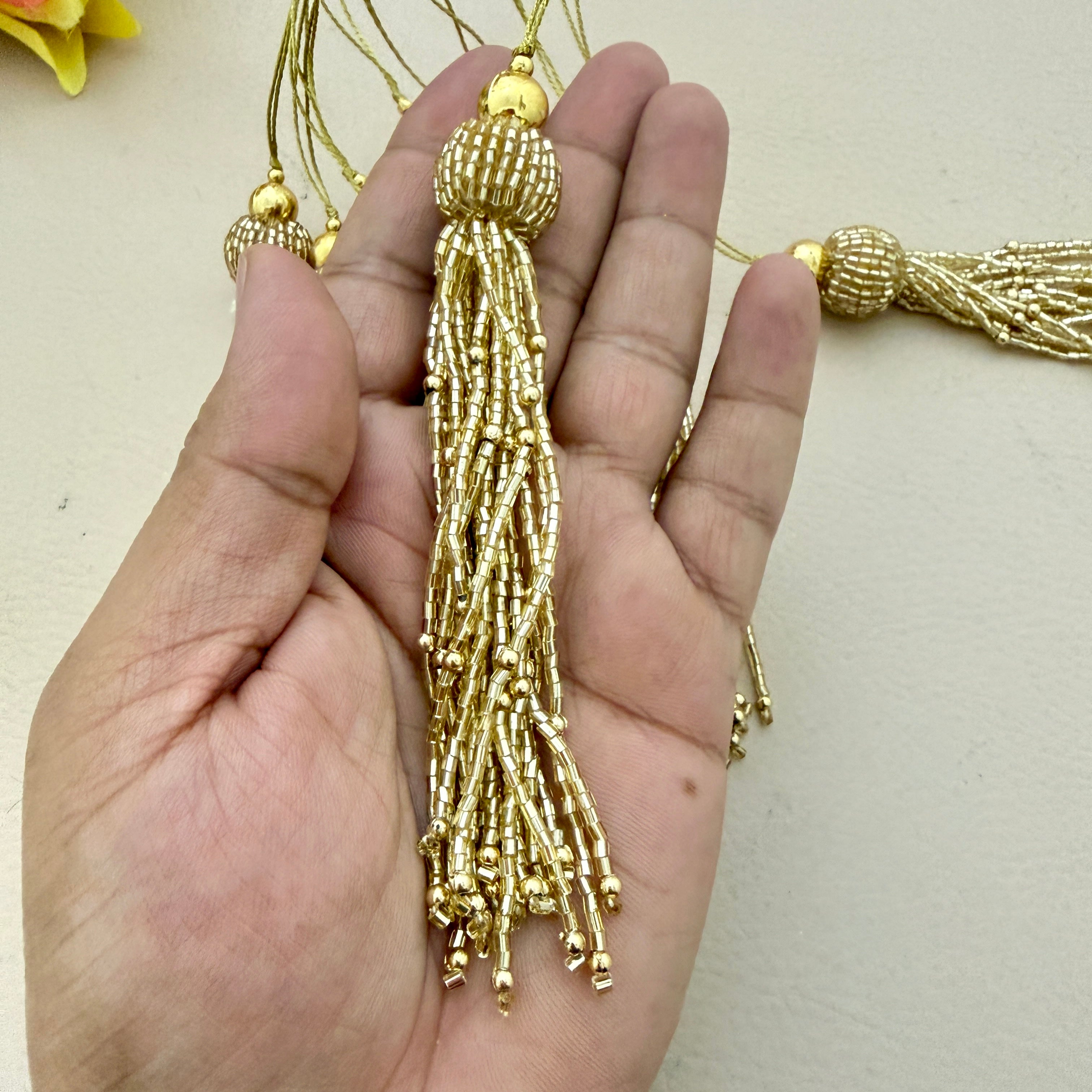 Gold tassel held in a hand against a neutral background