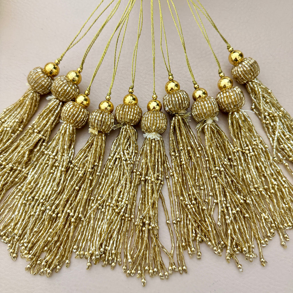 Gold tassels with beads on a light background