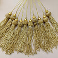 Gold tassels with beads on a light background