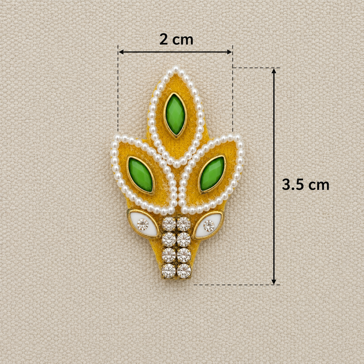 Decorative brooch with green gemstones and gold accents, shown with measurements on a beige background.
