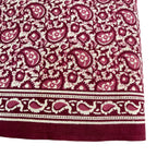 Close-up of a fabric with a paisley pattern in red and white on a white background