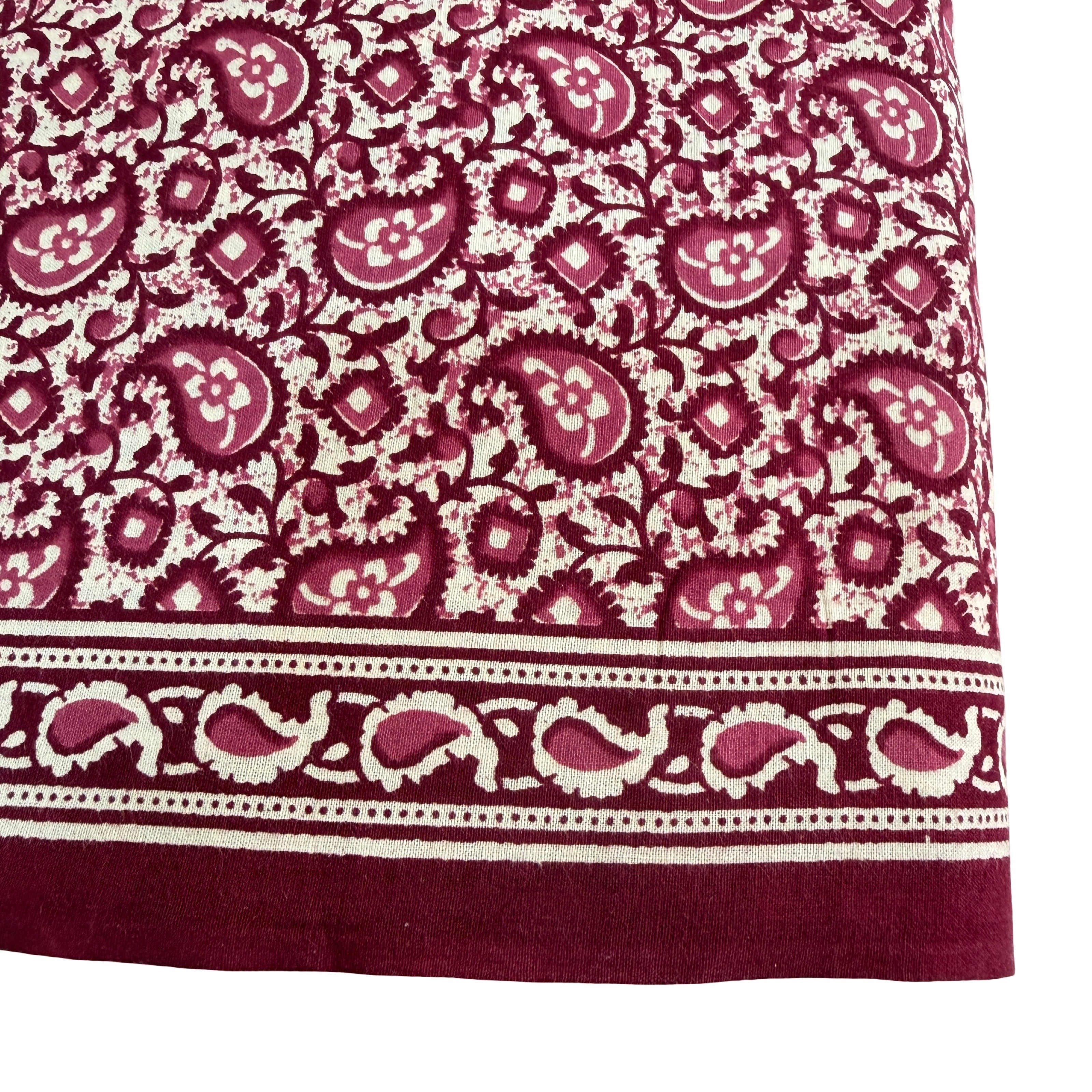 Close-up of a fabric with a paisley pattern in red and white on a white background