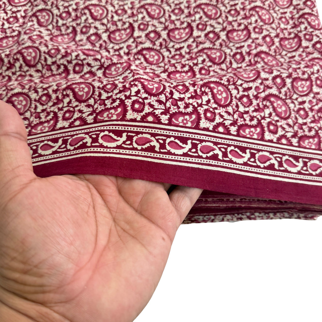 Hand holding a piece of fabric with a red and white pattern