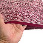 Hand holding a piece of fabric with a red and white pattern