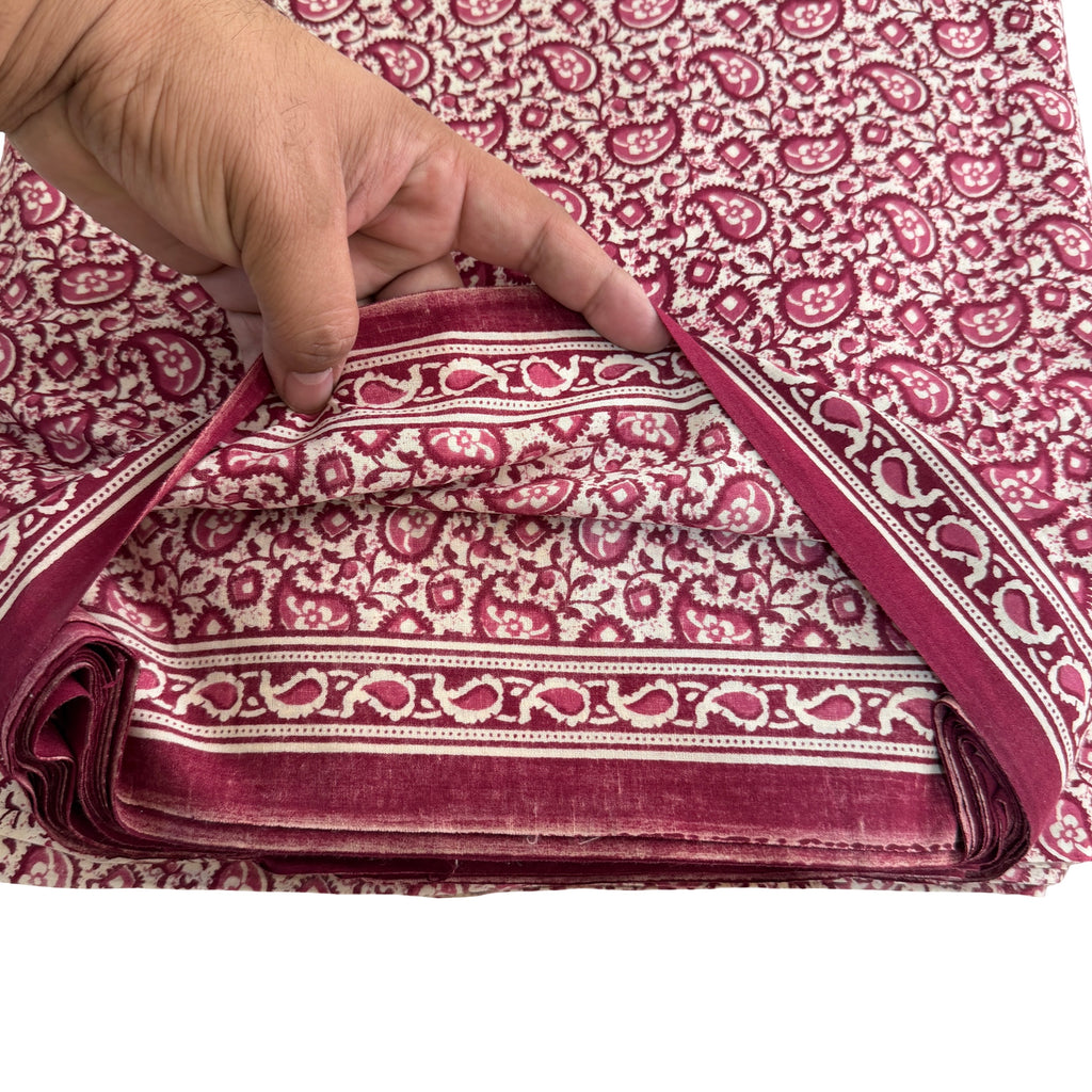 Folded fabric with red and white pattern held by a hand