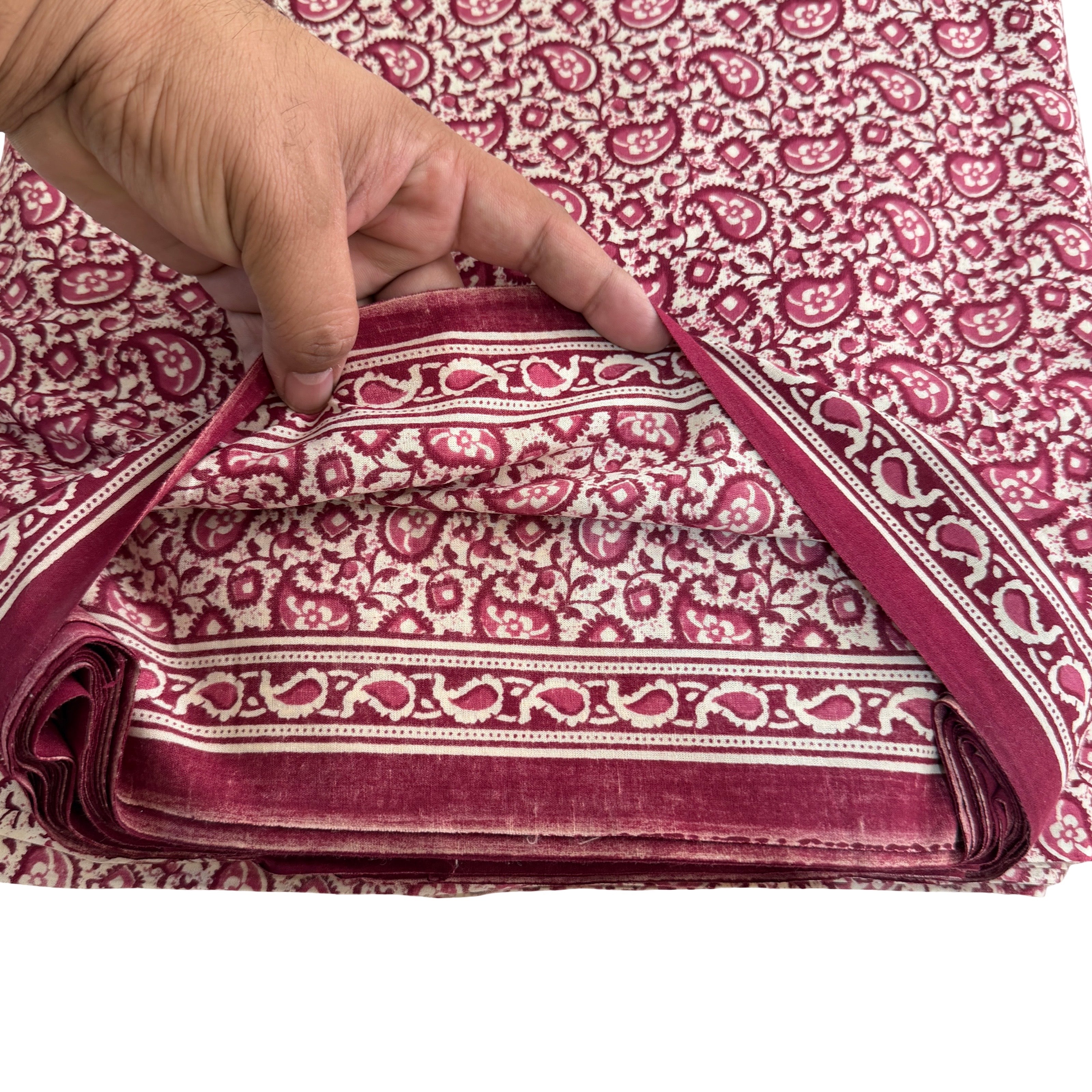 Folded fabric with red and white pattern held by a hand