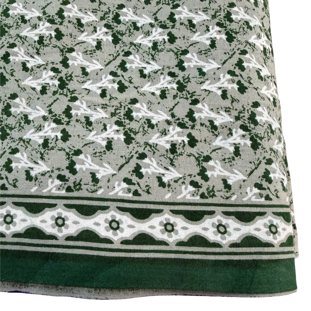 Textile with a pattern of small white shapes on a gray background, bordered by green and white geometric design.