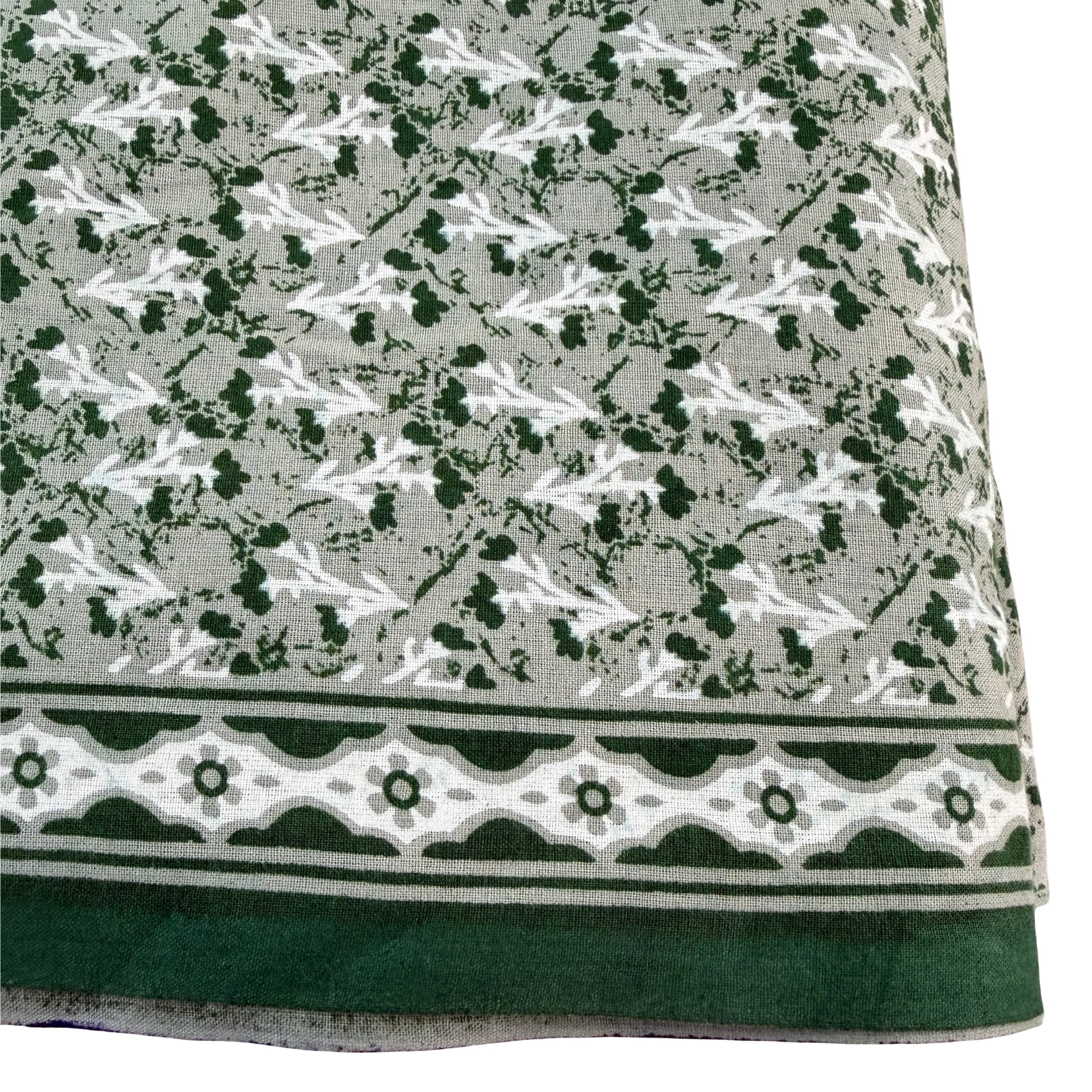 Textile with a pattern of small white shapes on a gray background, bordered by green and white geometric design.