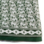Textile with a pattern of small white shapes on a gray background, bordered by green and white geometric design.