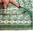 Green and white patterned fabric being held by a hand
