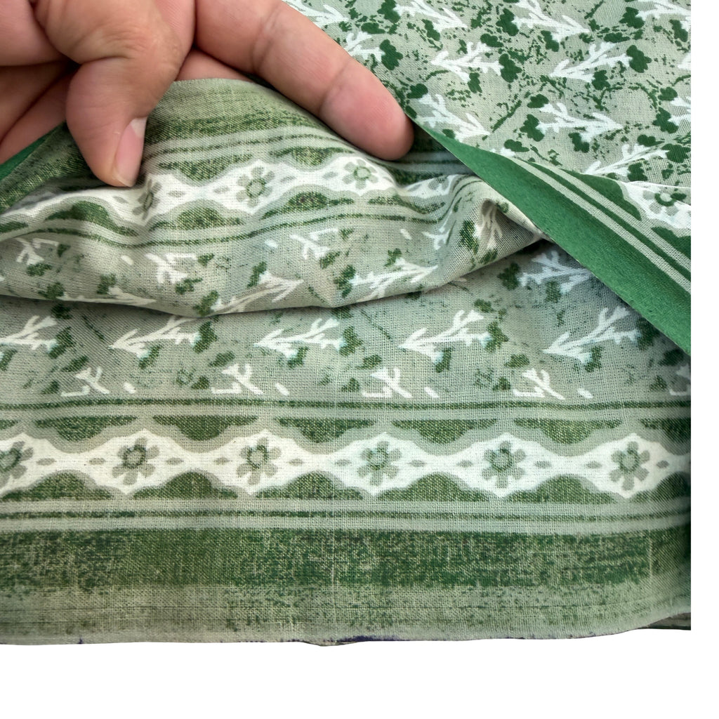Green and white patterned fabric being held by a hand