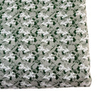 Fabric with a pattern of white and green shapes on a gray background