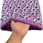 Hand holding a folded purple and white patterned fabric