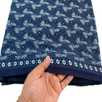 Hand holding a folded blue fabric with white floral patterns on a white background