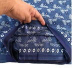 Hand holding a folded blue fabric with white floral patterns on a white background