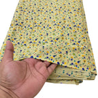 Hand holding a stack of yellow floral fabric