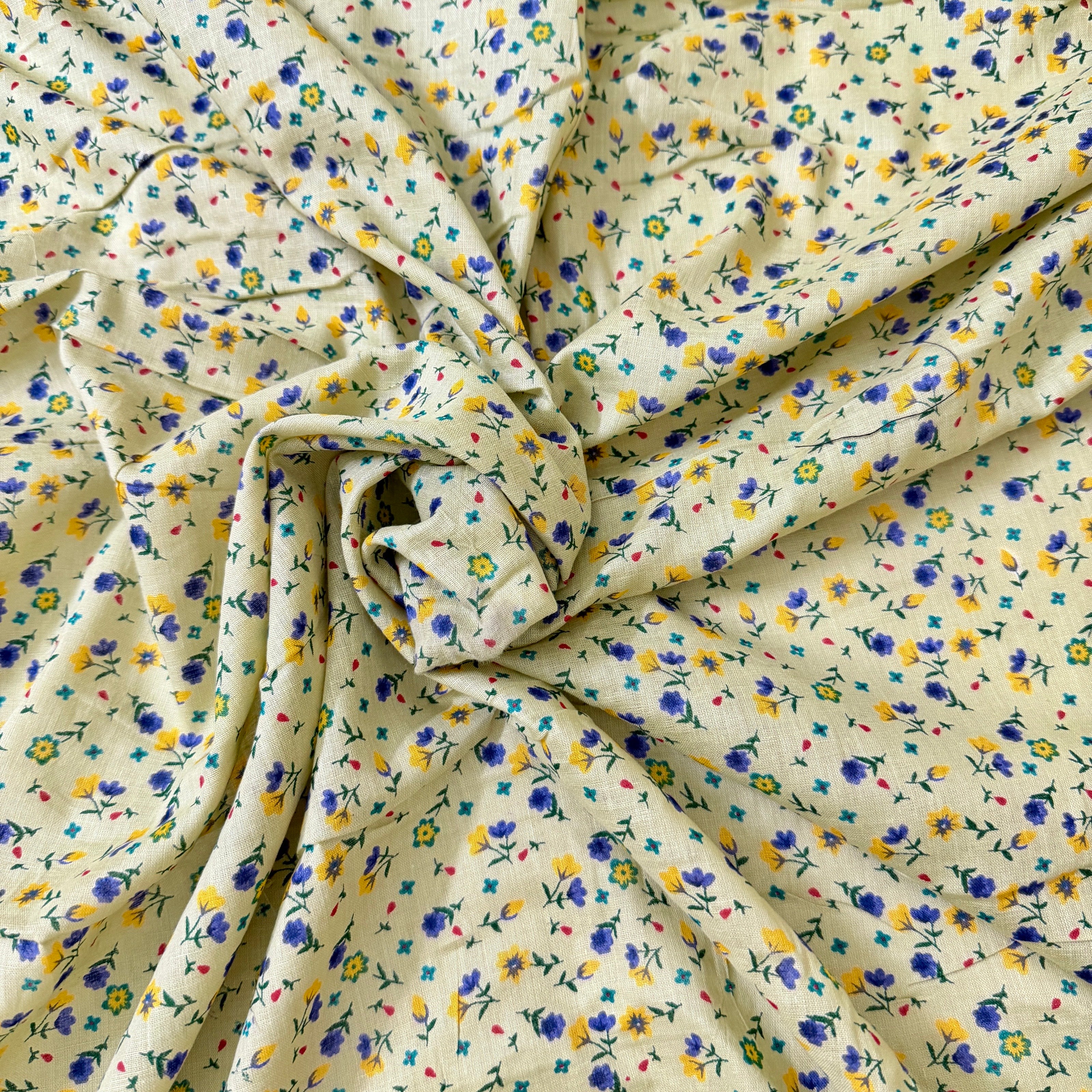 Floral fabric with small flowers in blue, yellow, and purple on a beige background