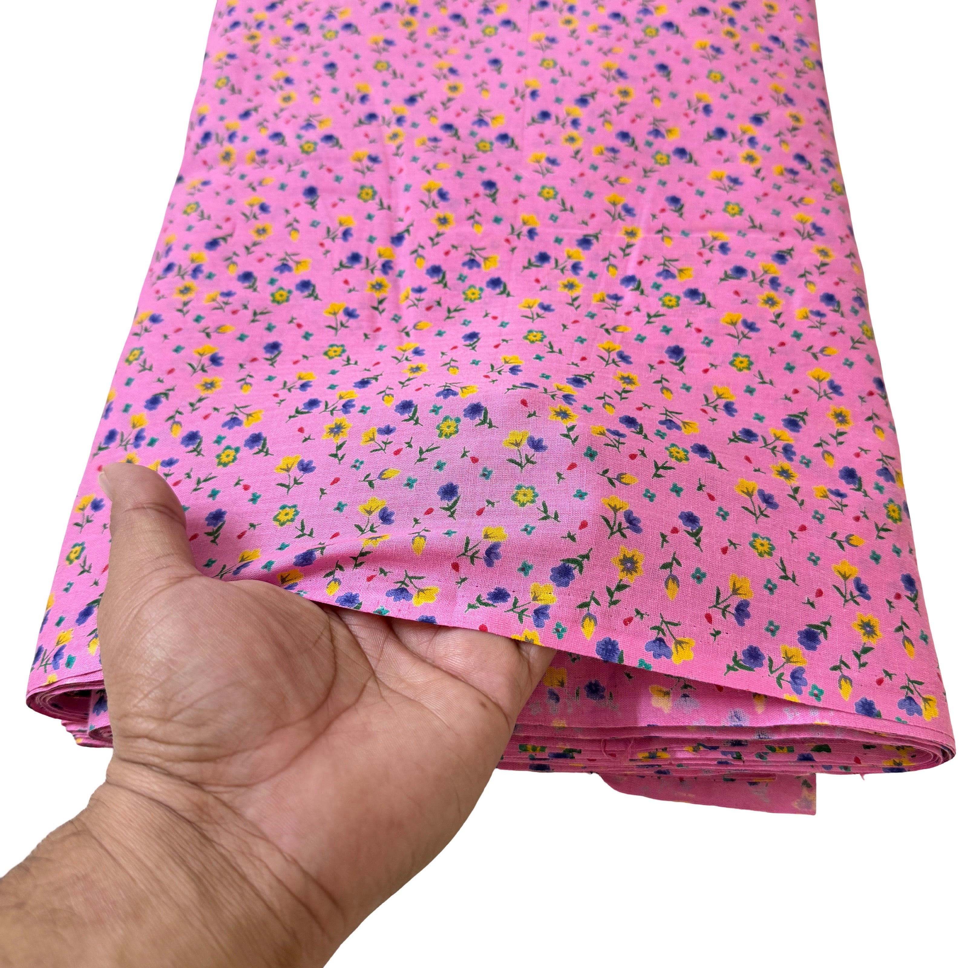 Hand holding a folded piece of pink fabric with small colorful floral pattern on a white background