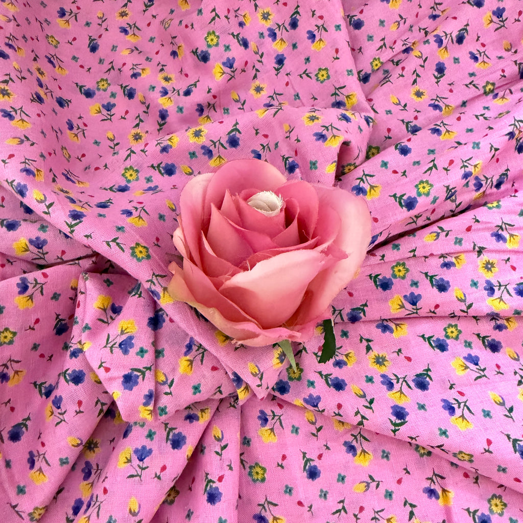 Pink fabric with floral pattern and a pink rose on top