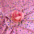 Pink fabric with floral pattern and a pink rose on top