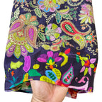 Colorful paisley patterned fabric held by a hand on a white background