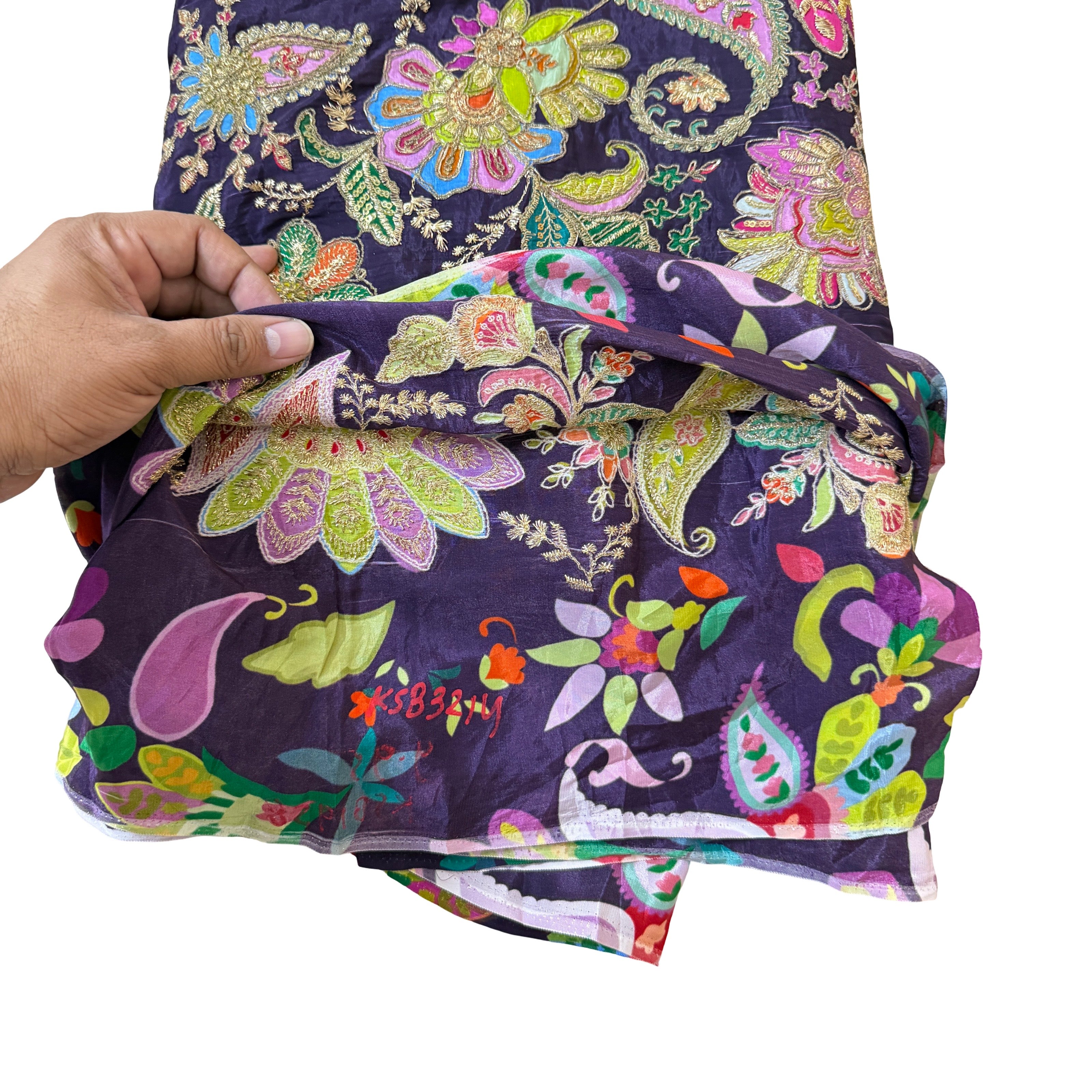 Colorful fabric with floral and paisley patterns held by a hand on a white background