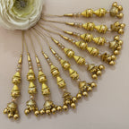 Gold hair accessories with decorative beads on a neutral background
