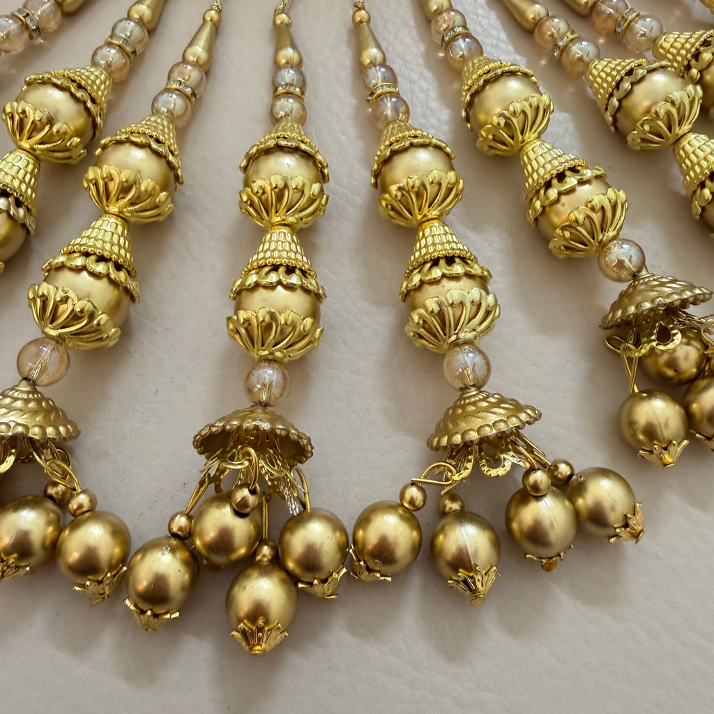 Close-up of a gold necklace with pearl-like beads on a light background