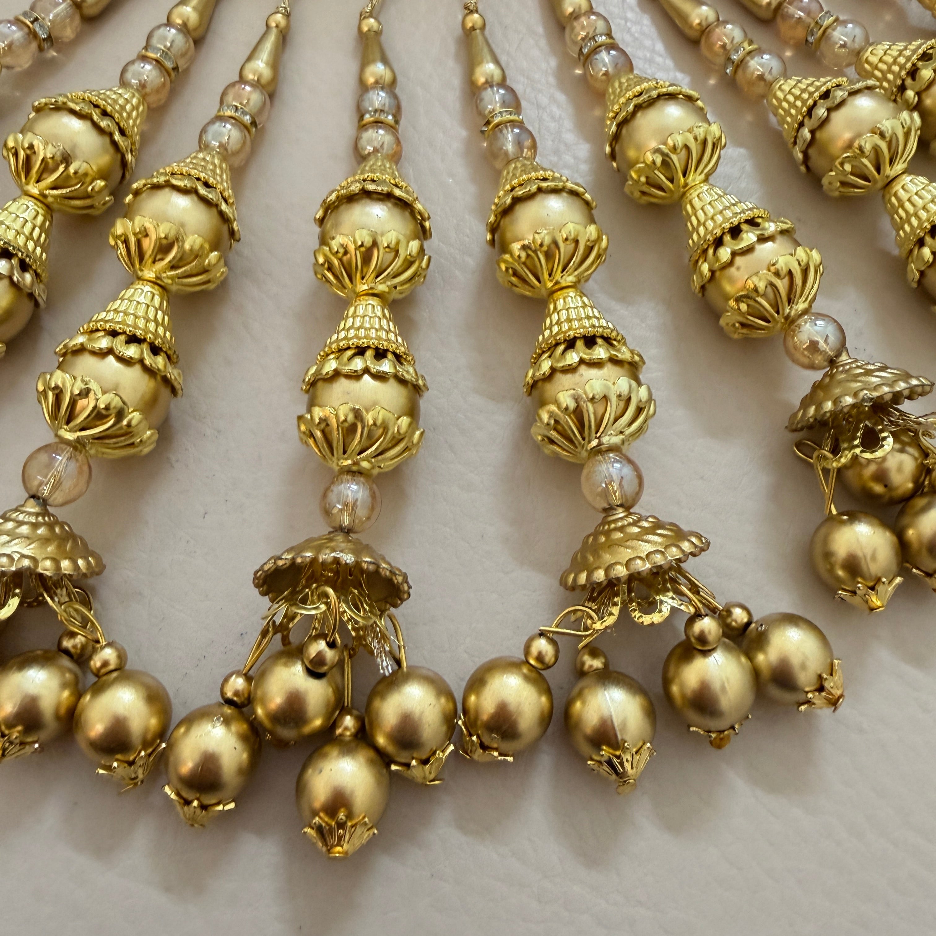 Close-up of a gold necklace with pearl-like beads on a light background