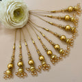 Set of gold hairpins with beads and pearls on a beige background