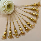 Set of gold hairpins with beads and pearls on a beige background
