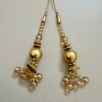 Pair of gold and pearl earrings on a light beige background