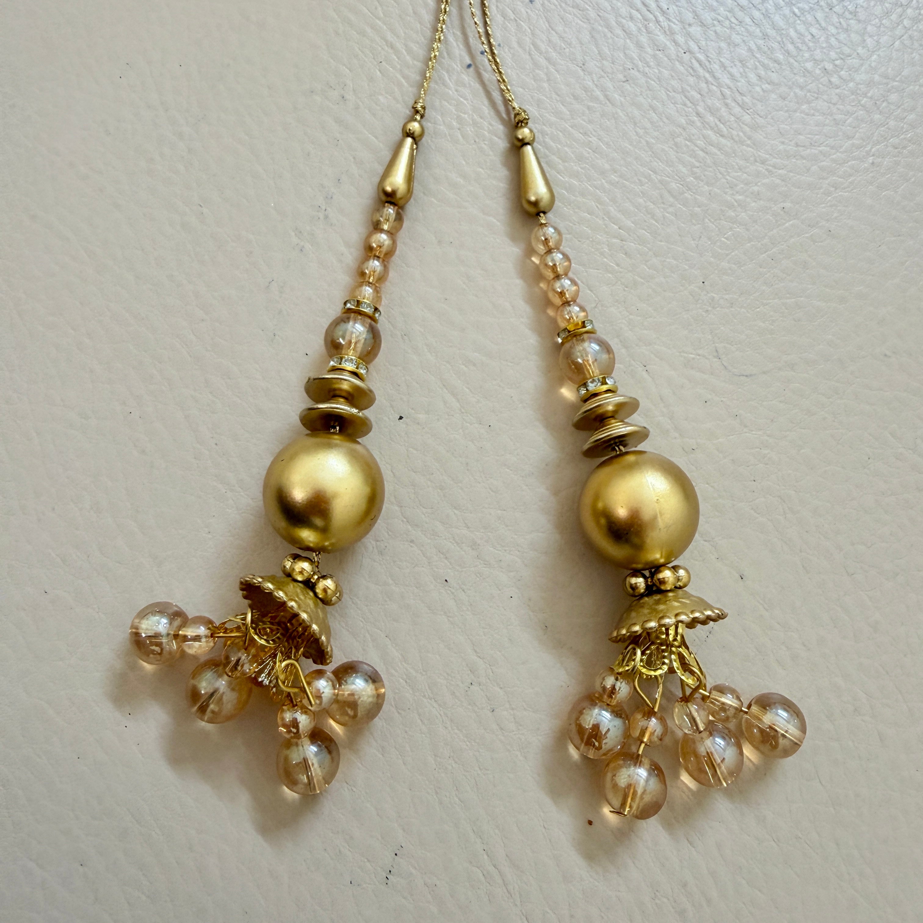 Pair of gold and pearl earrings on a light beige background