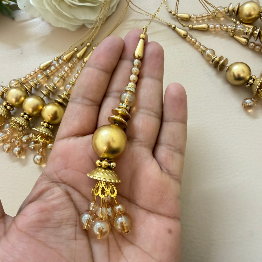 Gold and pearl necklace held in a hand with more jewelry in the background