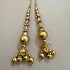Gold earrings with spherical beads and intricate designs on a light gray background