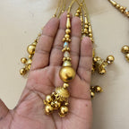 Gold necklace with decorative elements held in a hand against a neutral background