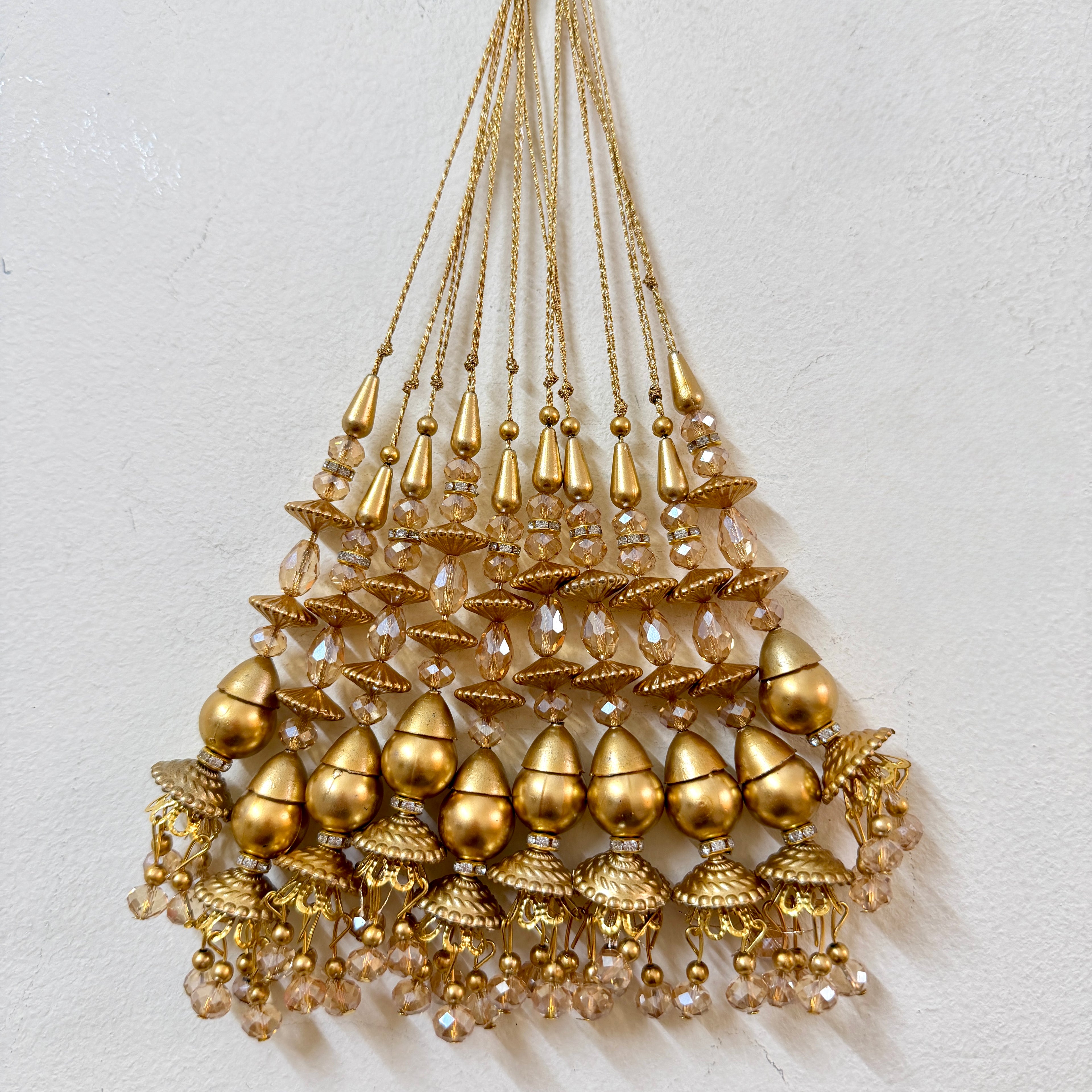 Gold beaded chandelier on a light gray background