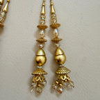 Gold earrings with crystal beads on a light beige background