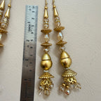 Gold earrings with crystal beads next to a ruler on a light background