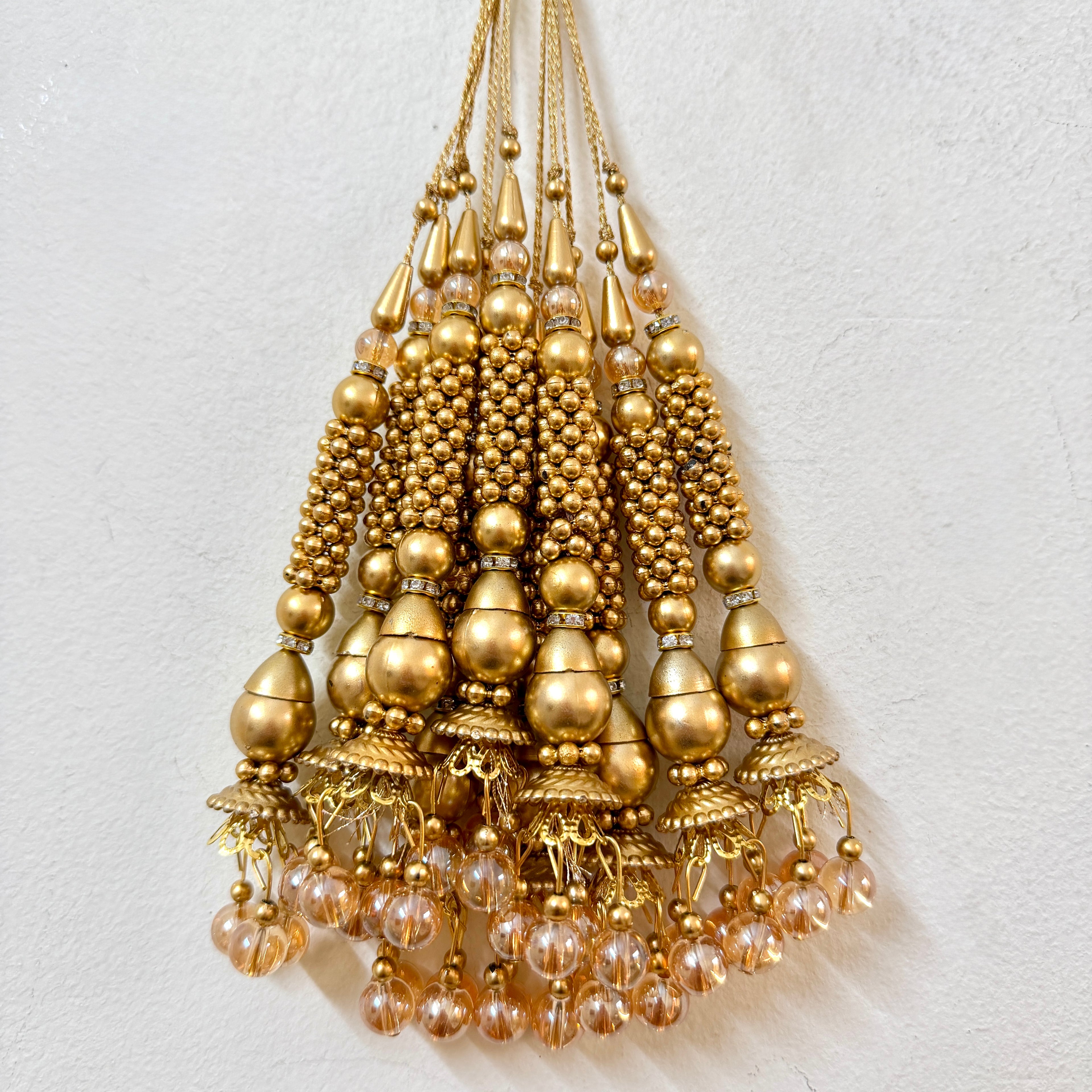 Gold beaded chandelier on a light gray background