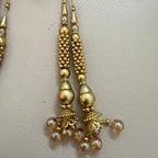 Gold earrings with beads on a light beige background