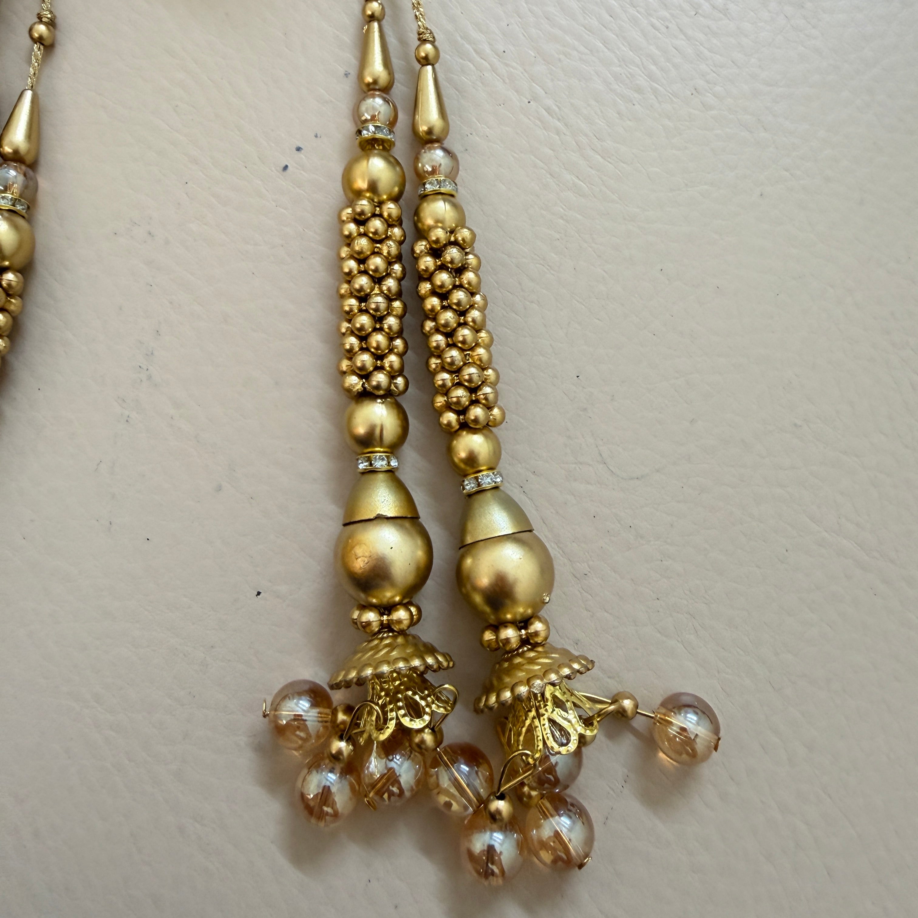 Gold earrings with beads on a light beige background