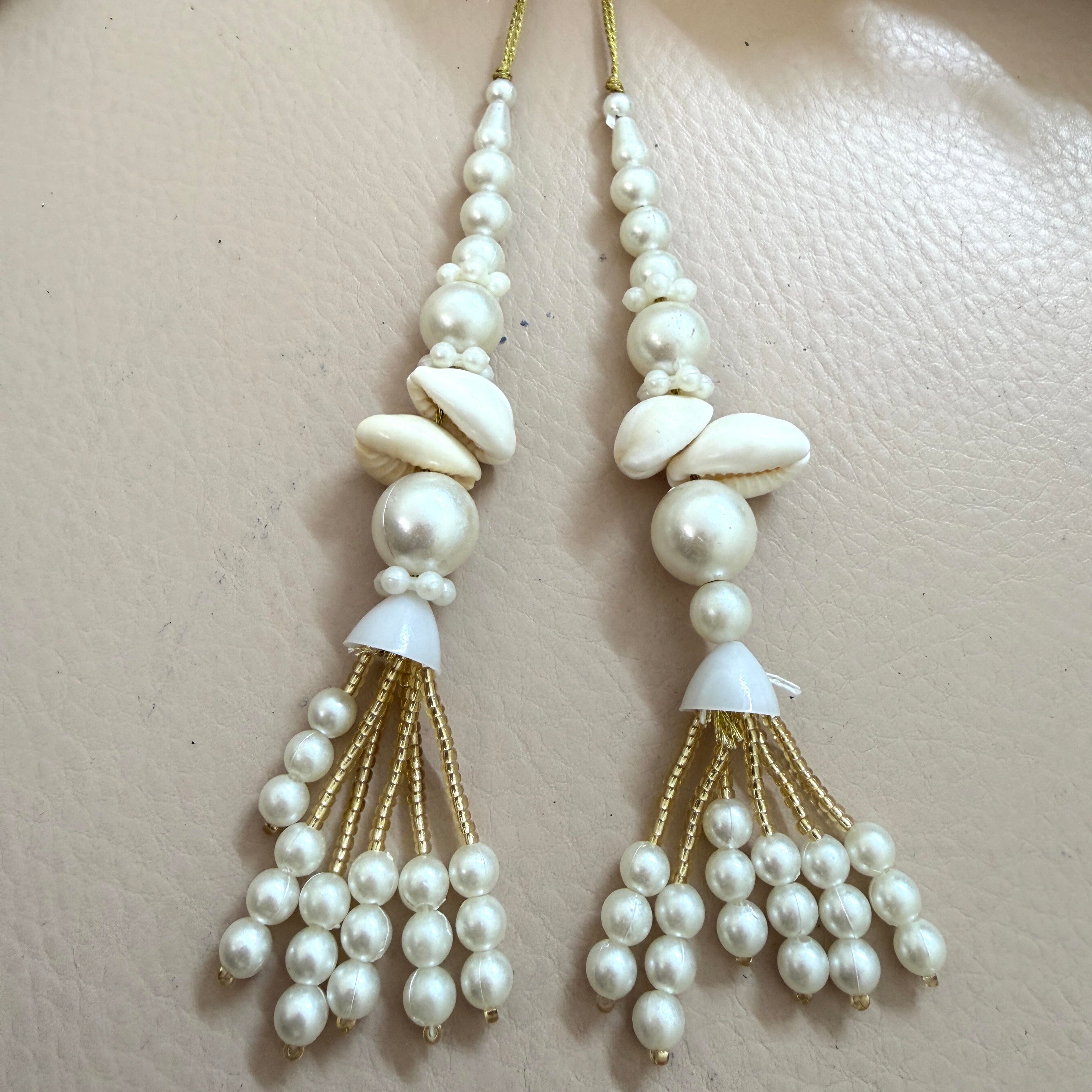 Pearl and gold tassel earrings on a beige background