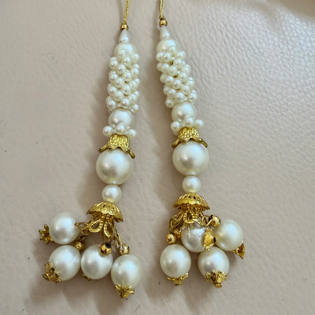 Pair of pearl earrings with gold accents on a light pink background