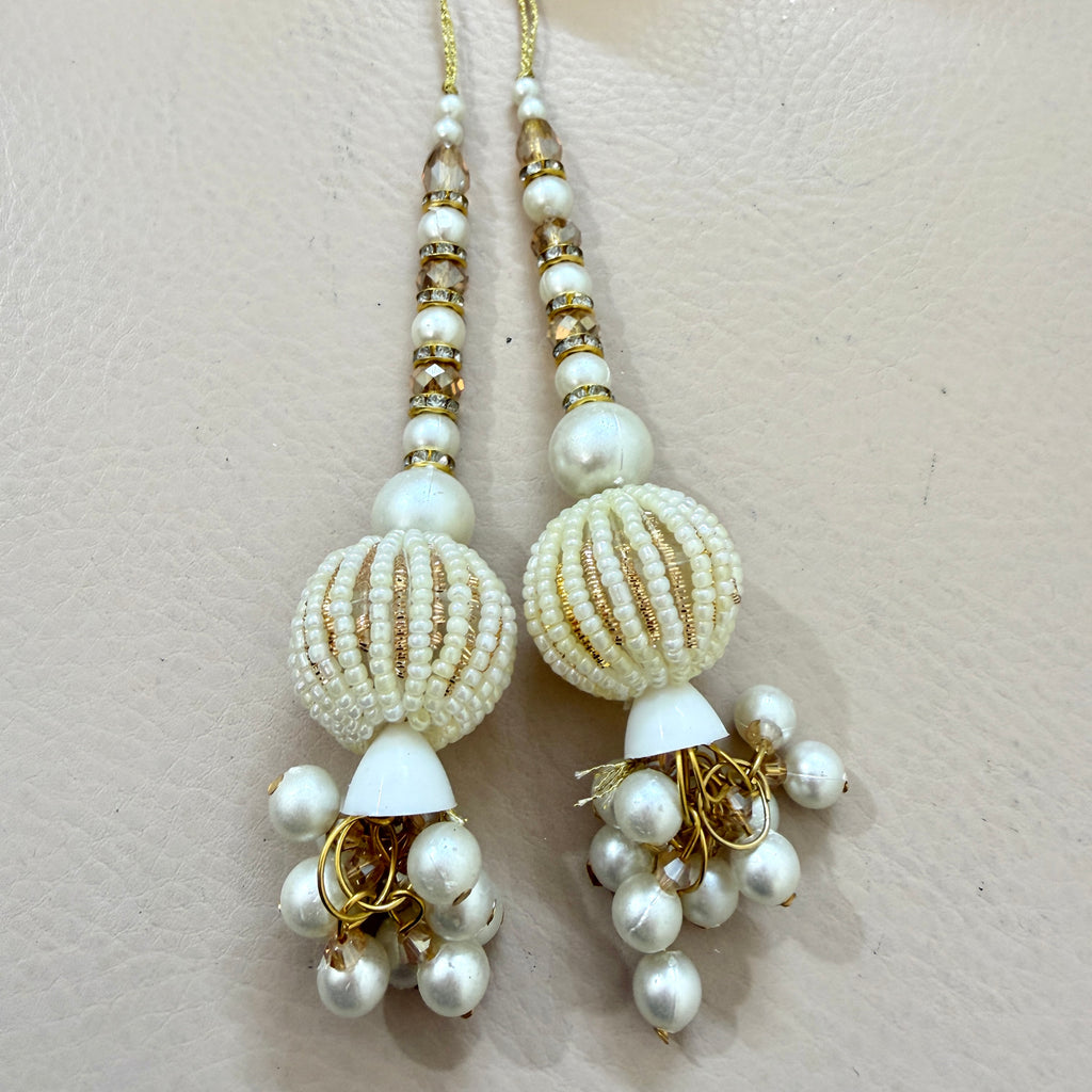 Pair of pearl and gold beaded earrings on a light beige background