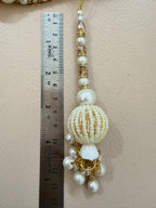 Decorative beaded accessory with a ruler for scale on a beige background