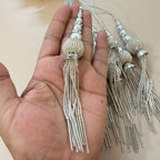 Silver beaded hairpins held in a hand with more hairpins on a beige background