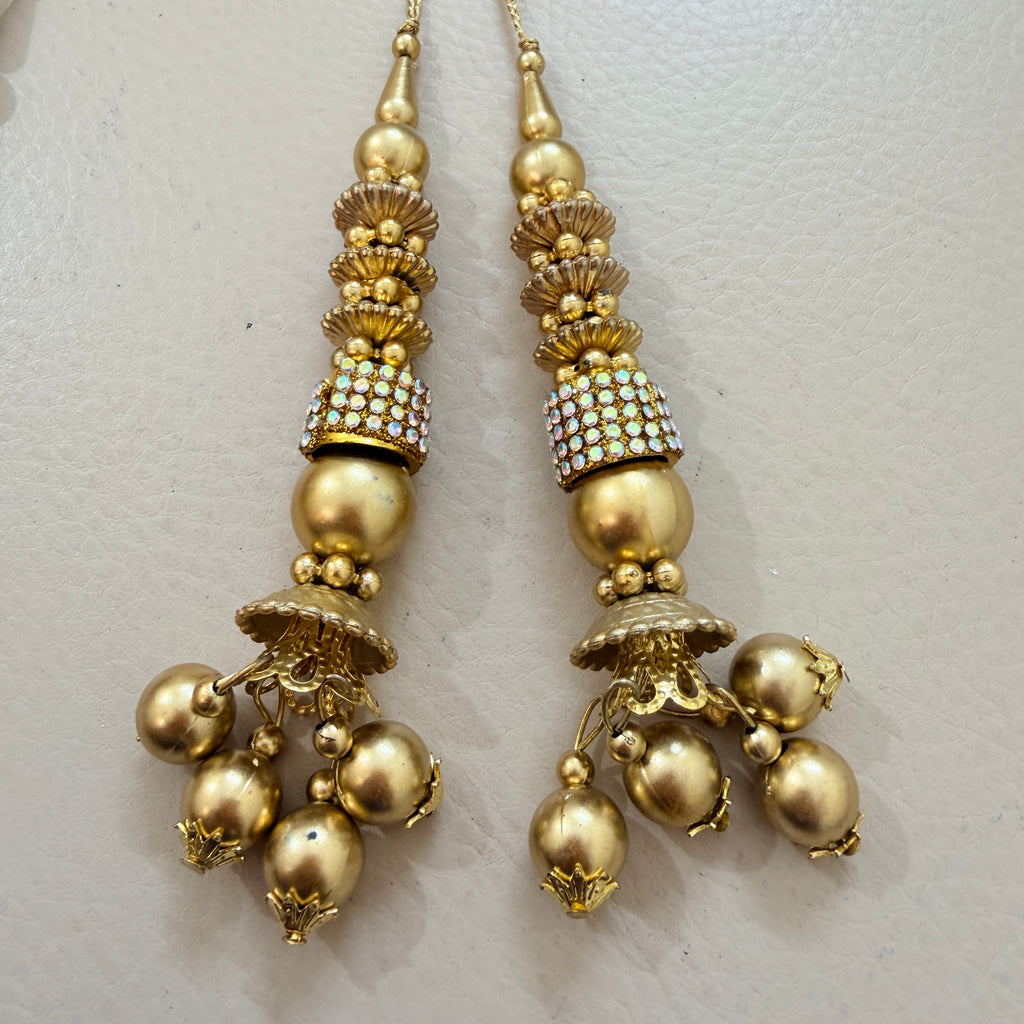 Pair of gold earrings with decorative elements on a light gray background