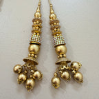 Pair of gold earrings with decorative elements on a light gray background